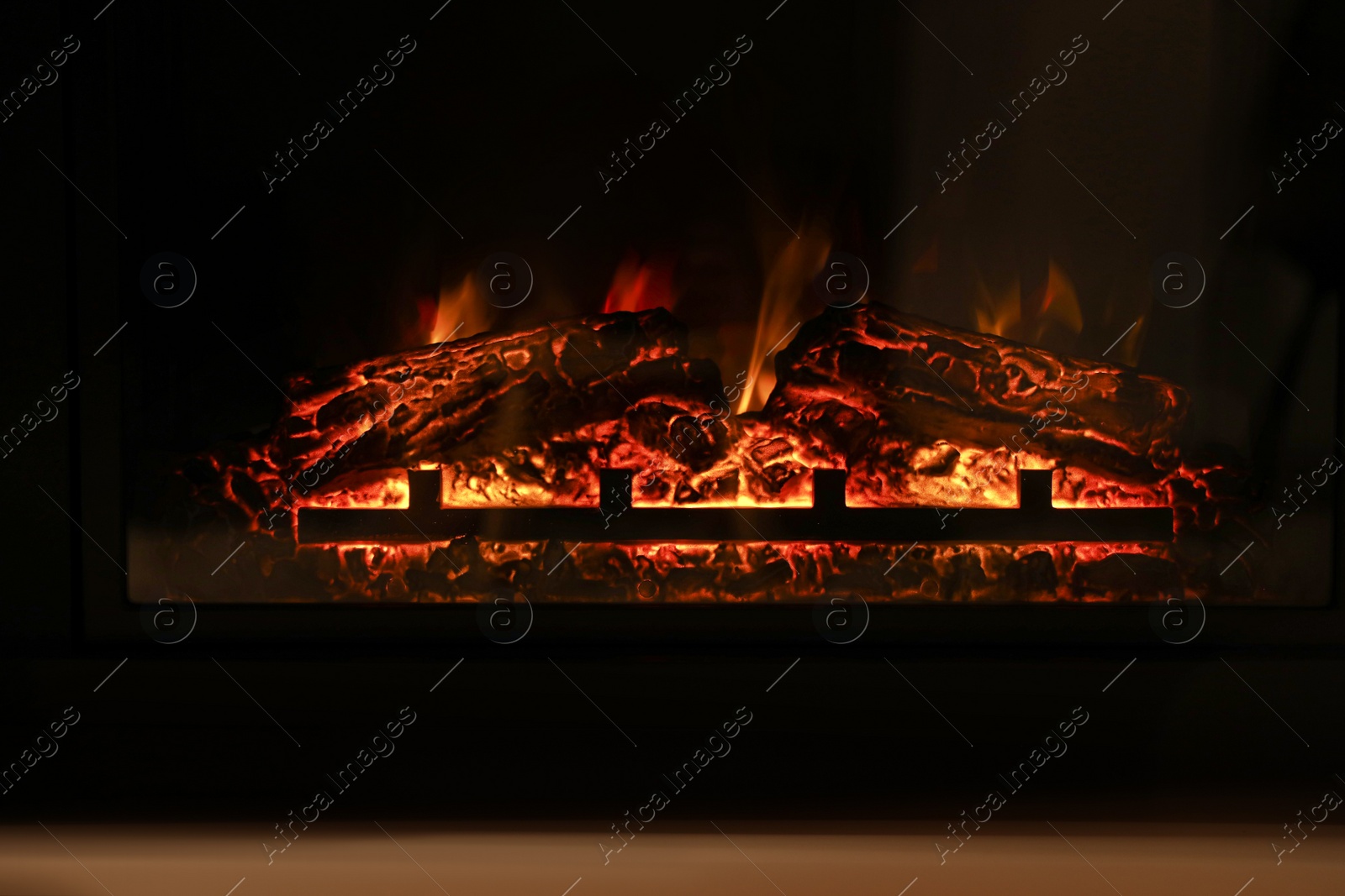 Photo of Firewood burning bright in elegant fireplace indoors, closeup