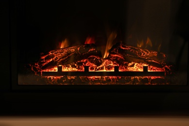 Firewood burning bright in elegant fireplace indoors, closeup