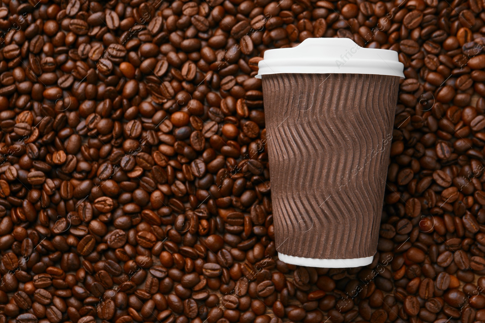 Photo of Coffee to go. Paper cup on roasted beans, top view and space for text