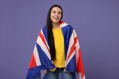 Happy young woman with flag of United Kingdom on violet background