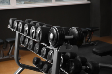 Photo of Dumbbells on rack in gym. Modern sport equipment