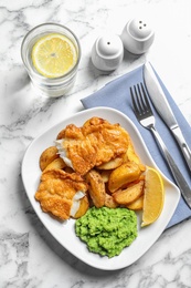 Photo of Plate with British traditional fish and potato chips on marble background, top view