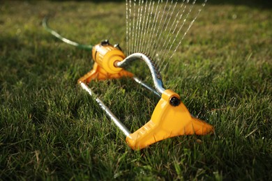 Automatic sprinkler watering green grass on lawn outdoors, closeup. Irrigation system