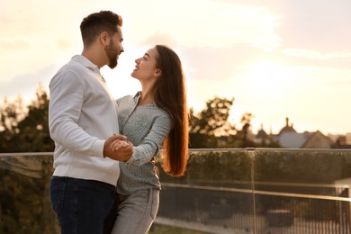 Lovely couple dancing together outdoors at sunset, space for text