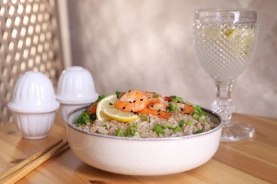 Photo of Tasty rice with shrimps and vegetables in bowl on wooden table