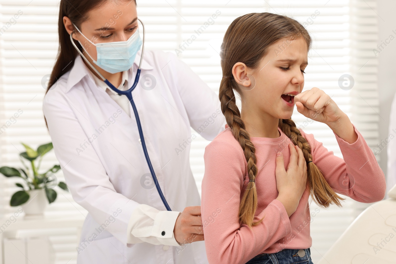 Photo of Doctor examining coughing girl in hospital. Cold symptoms