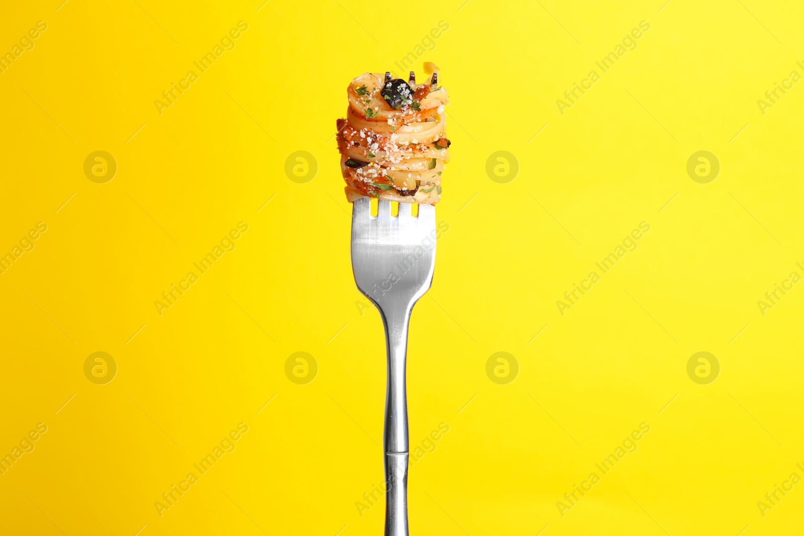 Photo of Fork with tasty pasta on yellow background
