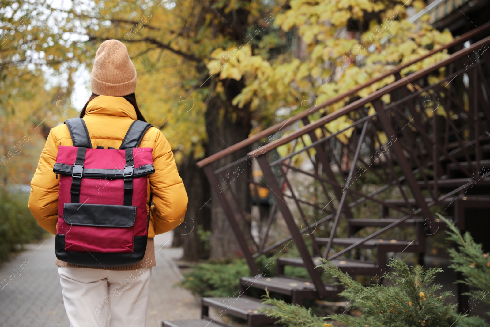 Photo of Female tourist with travel backpack on city street, back view. Urban trip