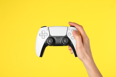 Photo of Woman with game controller on yellow background, closeup