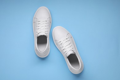 Photo of Pair of stylish white sneakers on light blue background, top view