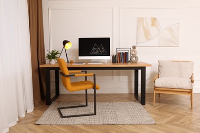 Stylish room interior with comfortable workplace near white wall