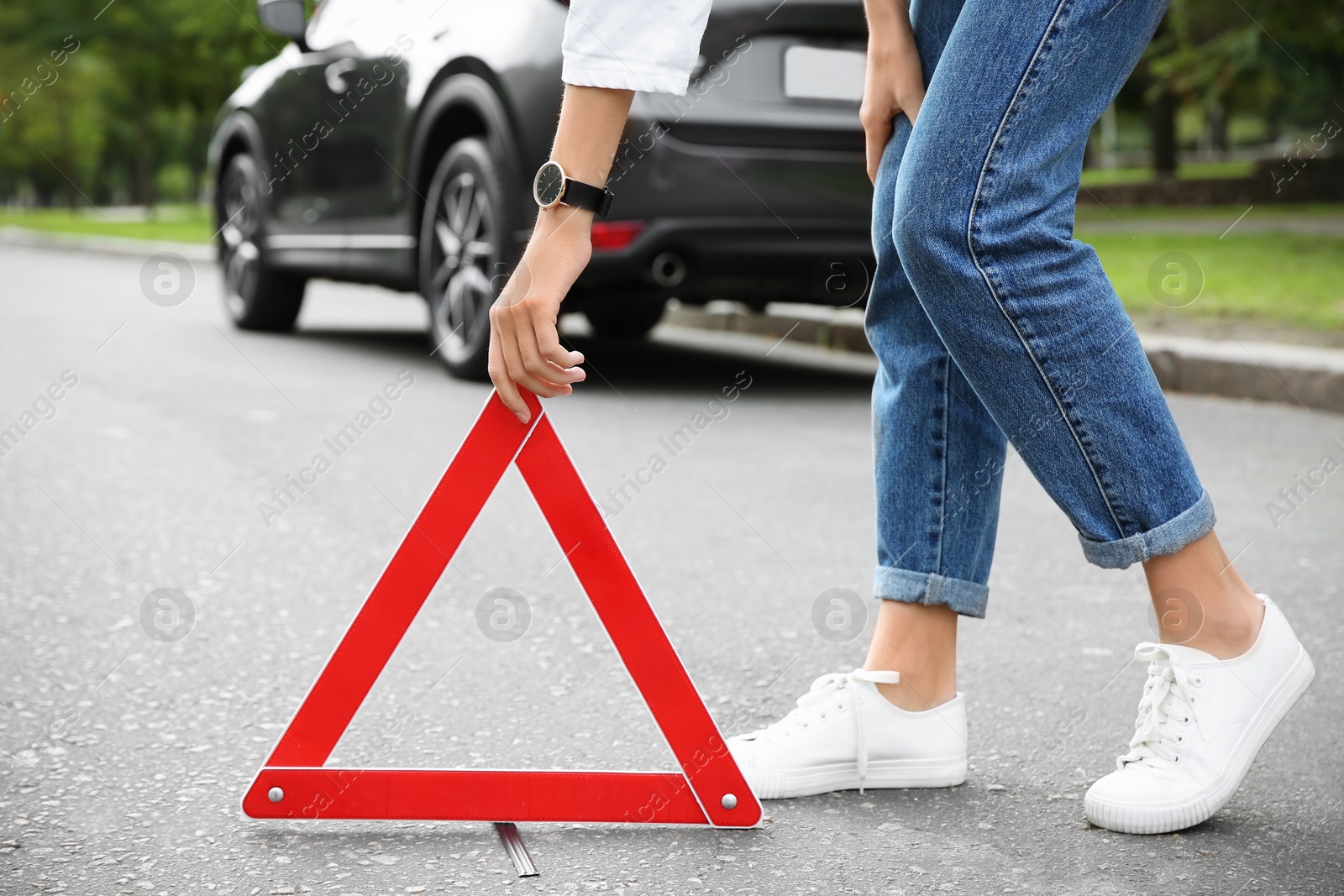 Photo of Woman putting emergency stop sign near broken car, closeup