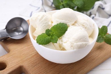 Delicious vanilla ice cream and mint in bowl on table, closeup
