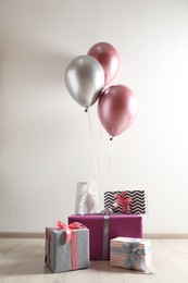 Gift boxes and balloons near white wall