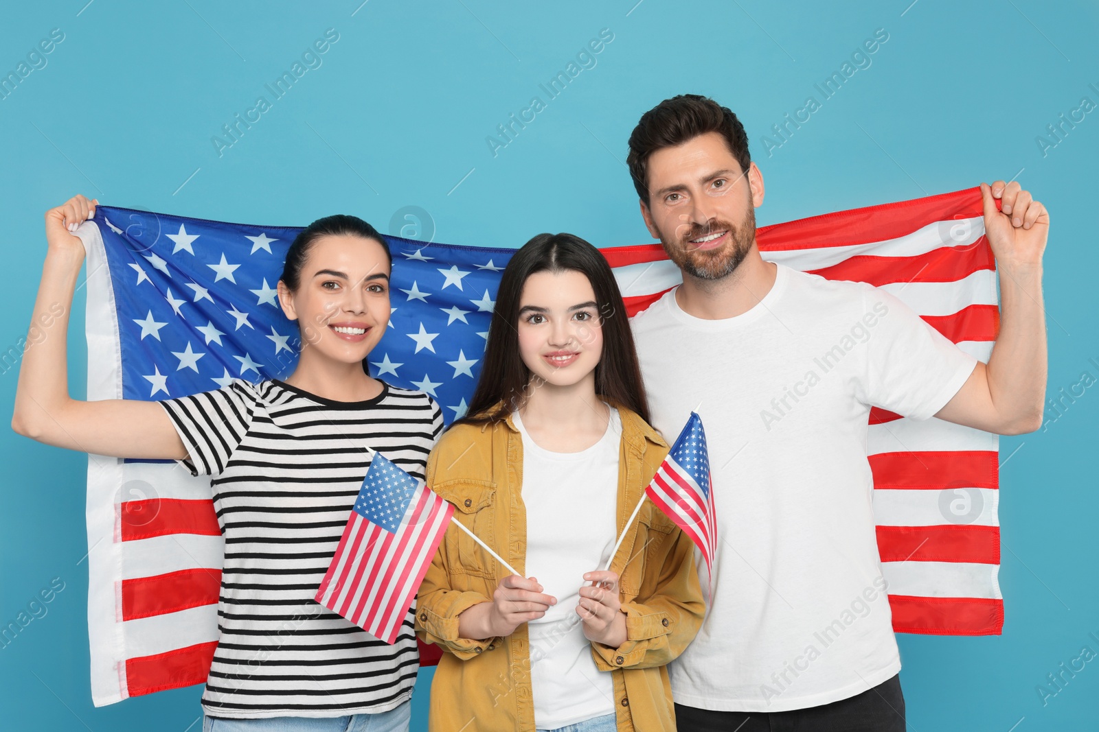 Photo of 4th of July - Independence Day of USA. Happy family with American flags on light blue background