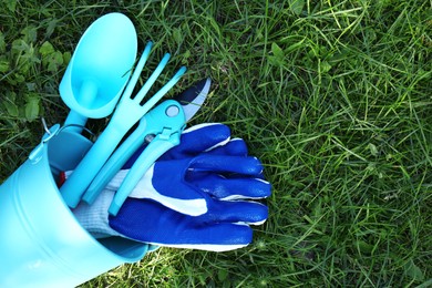 Photo of Bucket with gloves and gardening tools on grass outdoors, flat lay. Space for text