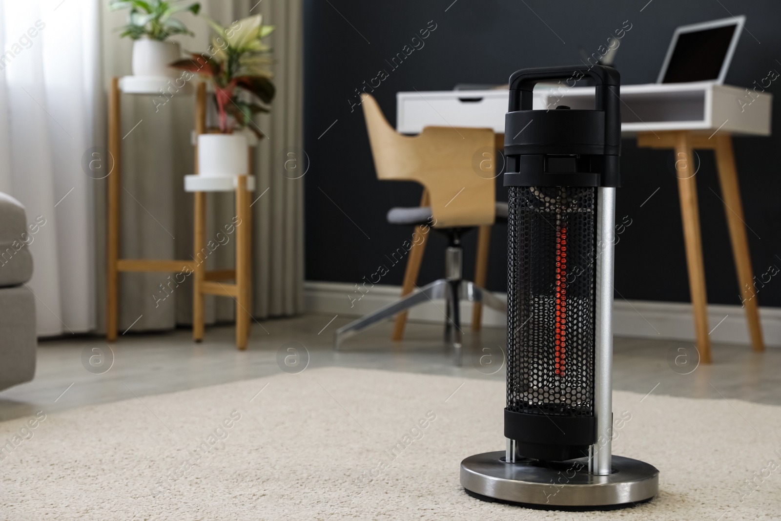 Photo of Modern electric halogen heater on floor in room interior