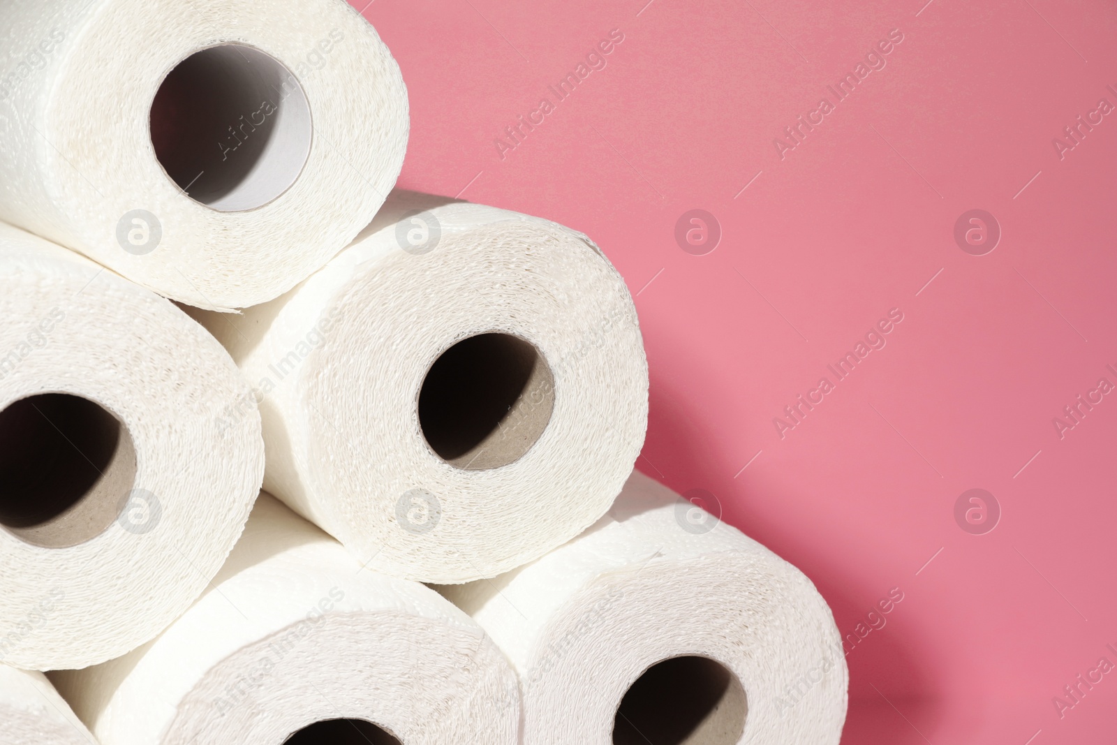 Photo of Many rolls of paper towels on pink background, closeup. Space for text