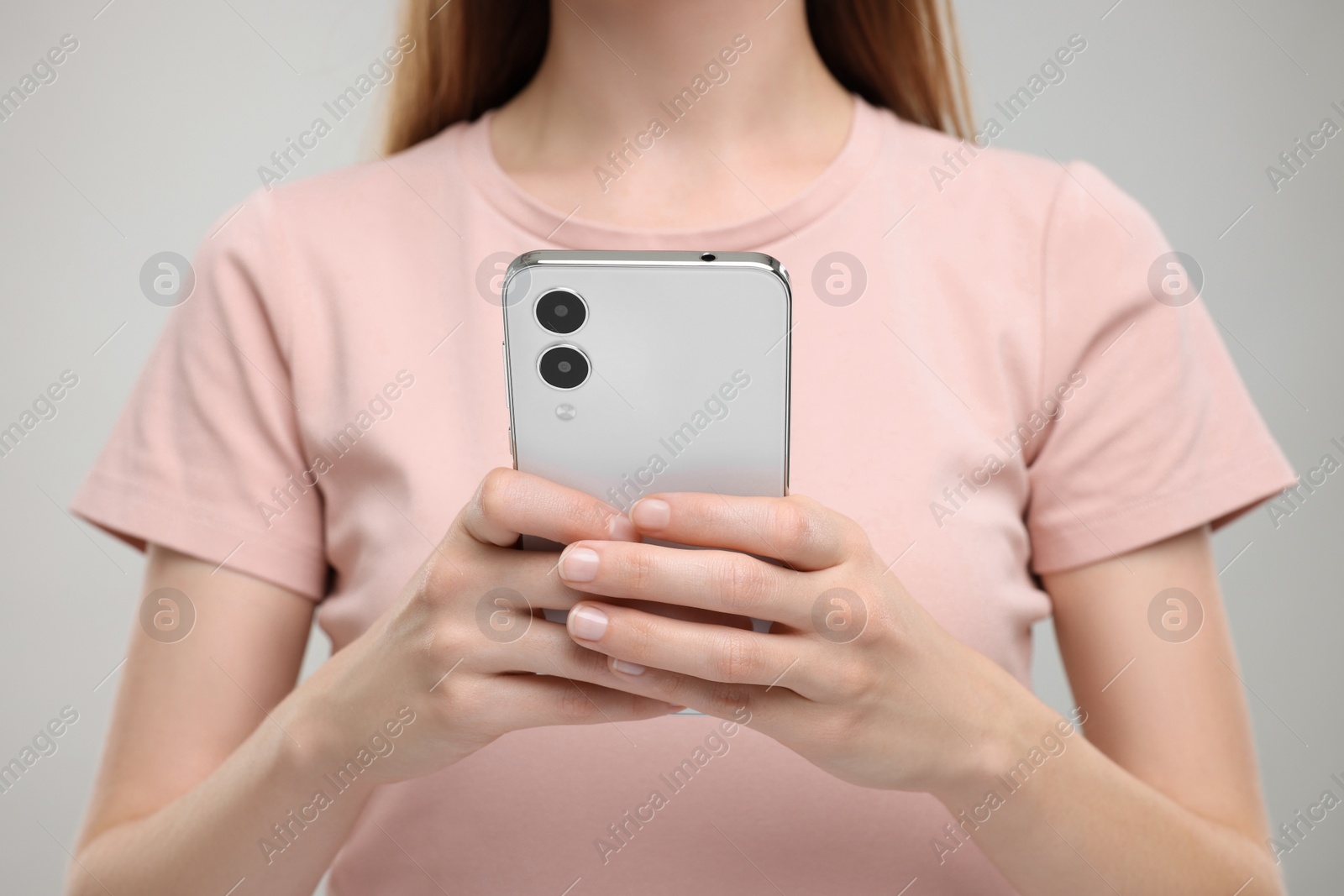 Photo of Woman sending message via smartphone on grey background, closeup