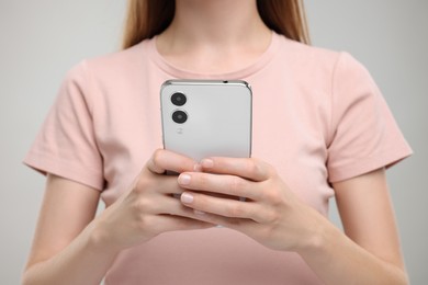 Photo of Woman sending message via smartphone on grey background, closeup