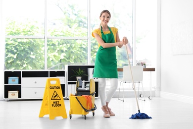 Photo of Young woman with mop and bucket cleaning office