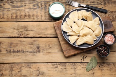 Photo of Tasty dumplings served on wooden table, flat lay. Space for text