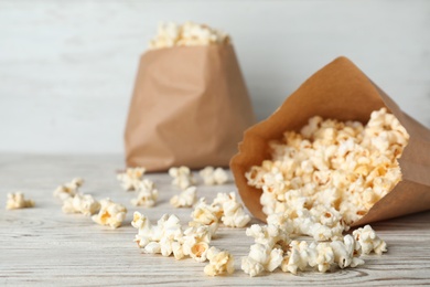 Photo of Overturned paper bag with popcorn on wooden table. Space for text