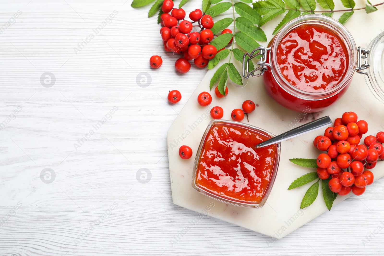 Photo of Flat lay composition with delicious rowan jam on white wooden table. Space for text