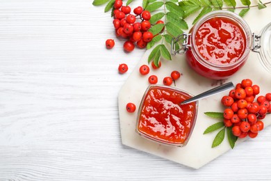 Flat lay composition with delicious rowan jam on white wooden table. Space for text