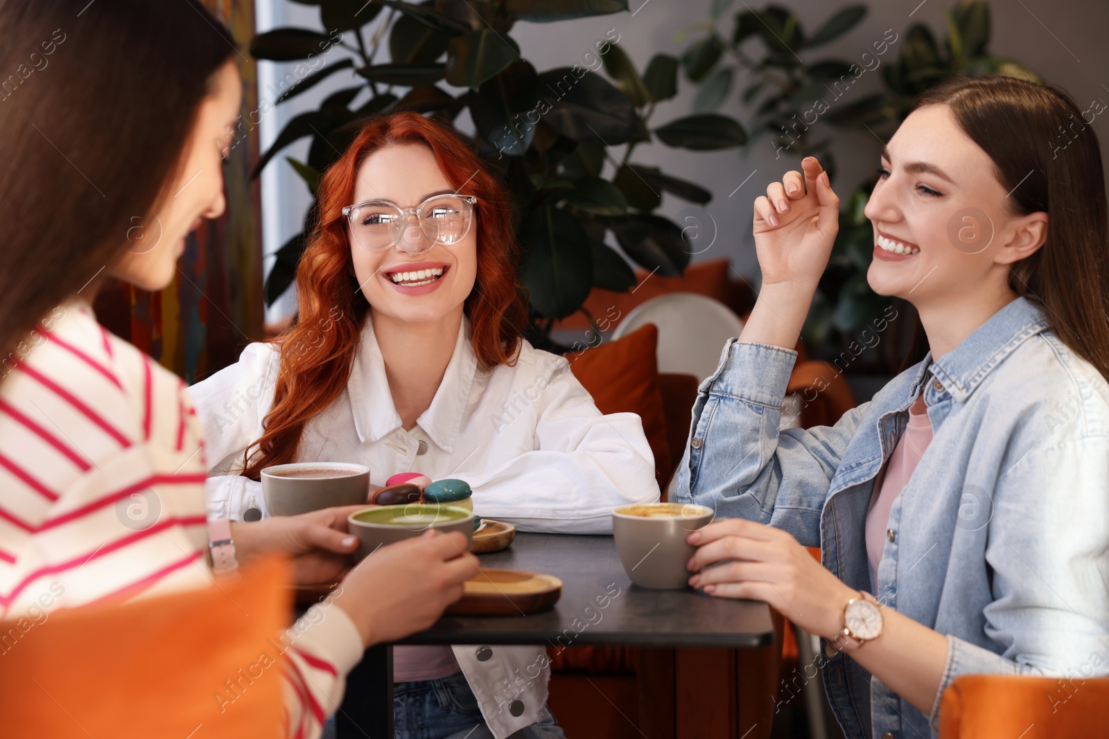 Photo of Happy friends talking and drinking coffee in cafe