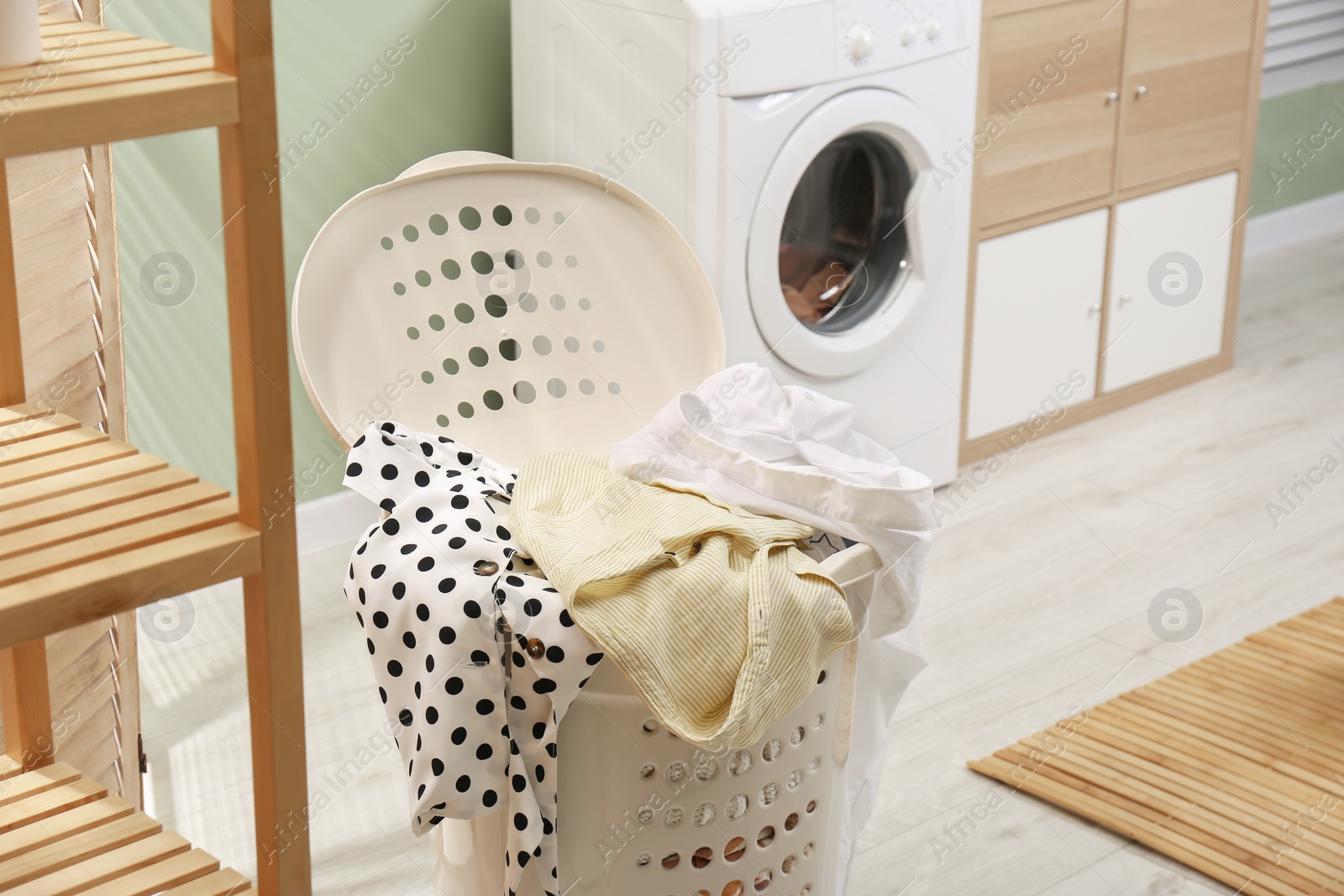 Photo of Laundry basket filled with clothes in bathroom. Space for text