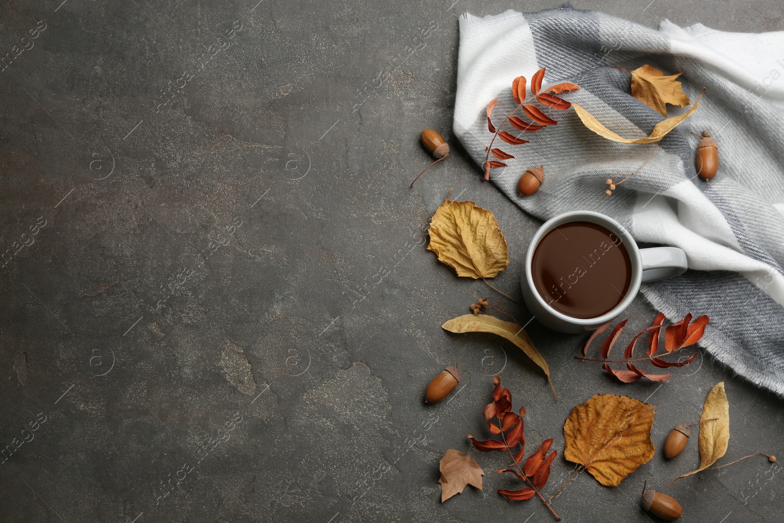 Photo of Flat lay composition with cup of hot drink and autumn leaves on grey table, space for text. Cozy atmosphere
