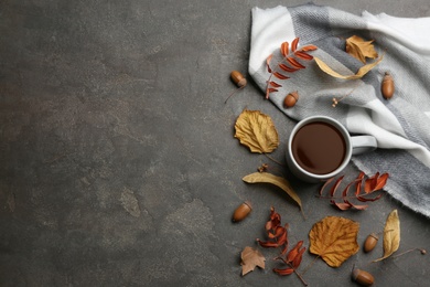 Flat lay composition with cup of hot drink and autumn leaves on grey table, space for text. Cozy atmosphere