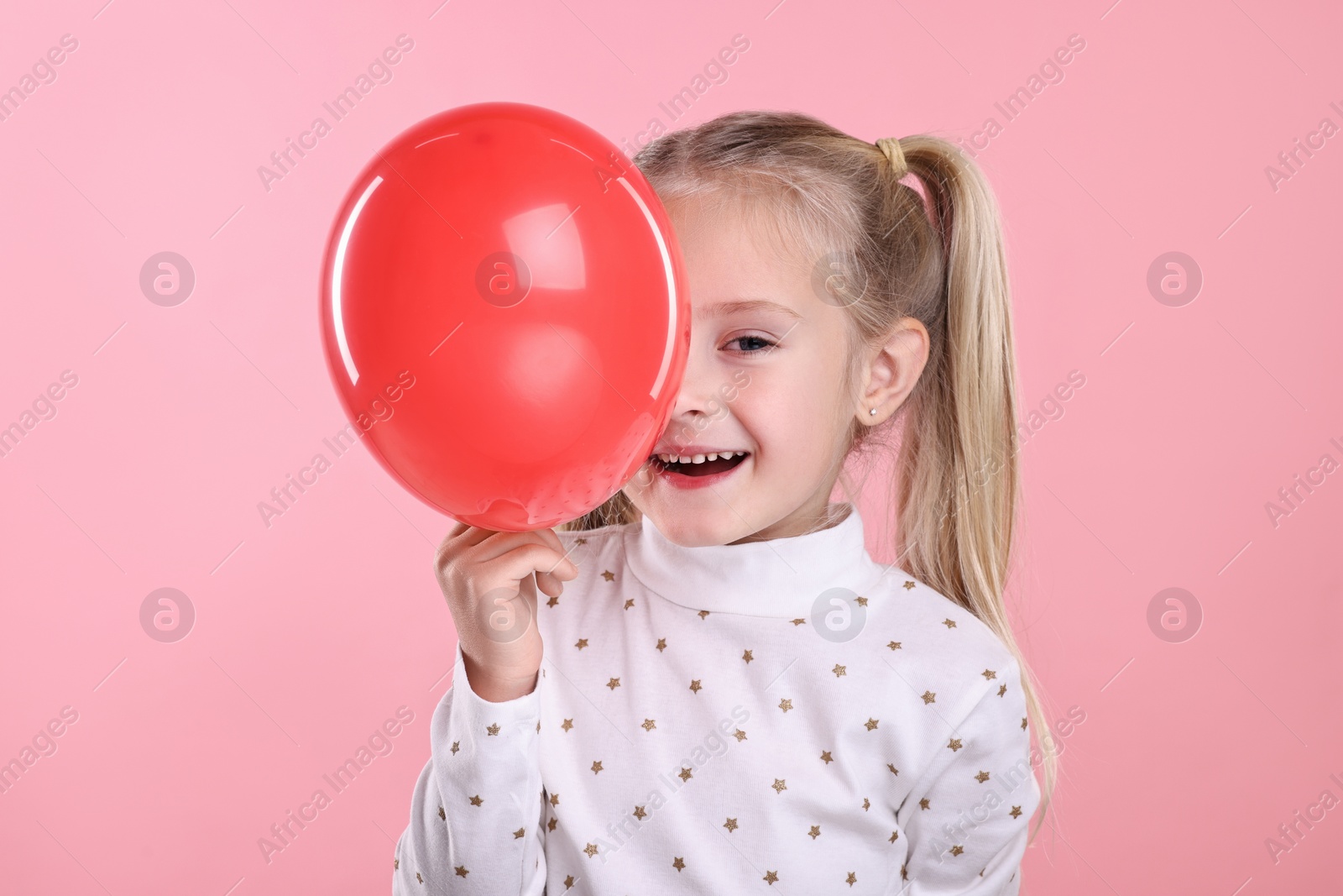 Photo of Cute little girl with red balloon on pink background