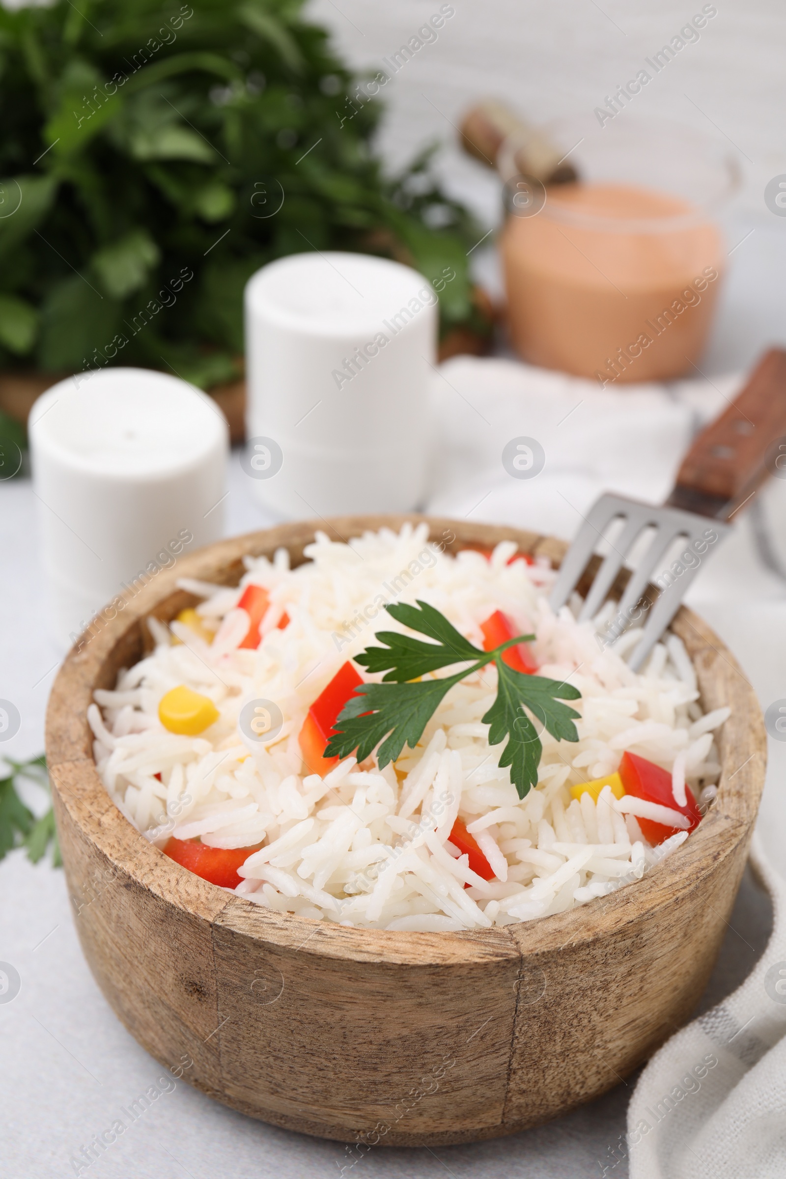 Photo of Bowl of delicious rice with vegetables and parsley served on table, closeup