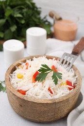 Photo of Bowl of delicious rice with vegetables and parsley served on table, closeup