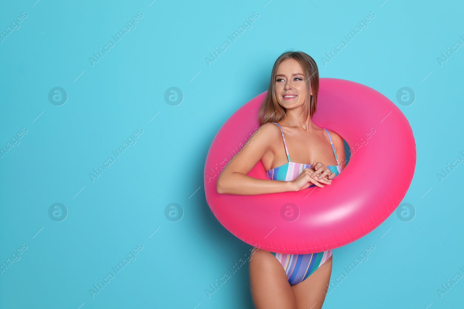 Photo of Sexy young woman in bikini with inflatable ring on color background