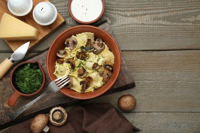 Photo of Delicious ravioli with mushrooms and ingredients on wooden table, flat lay. Space for text
