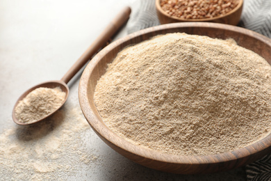 Image of Buckwheat flour in wooden bowl on table, closeup