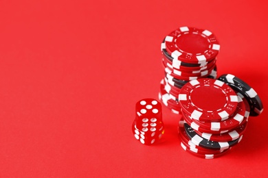 Photo of Poker chips and dices on red background, space for text