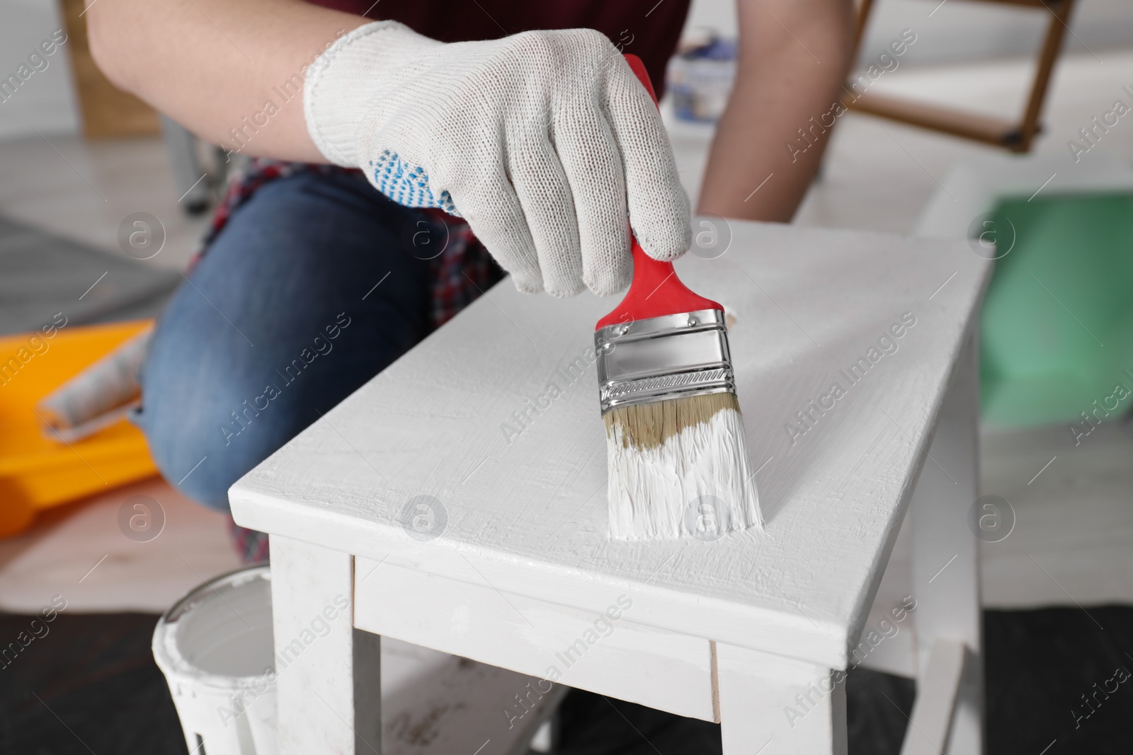 Photo of Man using brush to paint bekvam with white dye indoors, closeup