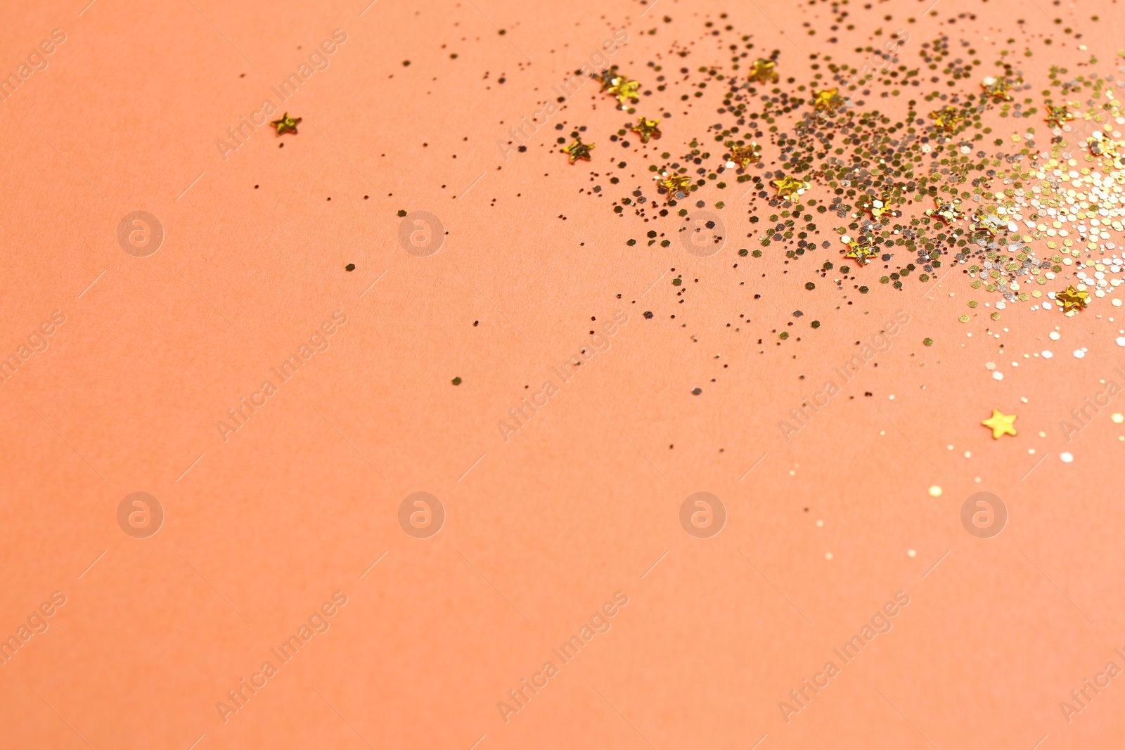 Photo of Shiny bright golden glitter on pale coral background. Space for text