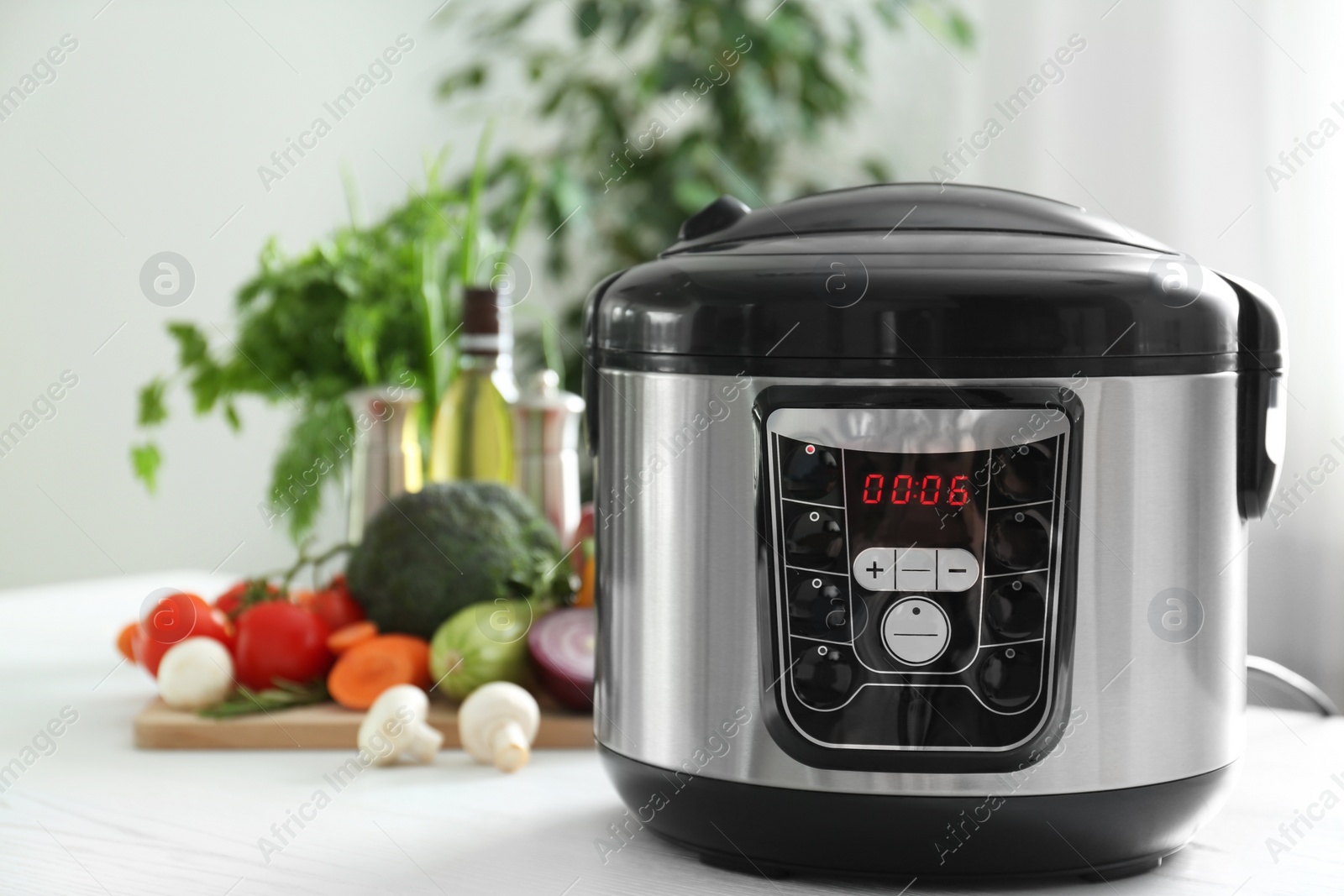 Photo of Modern multi cooker and products on table in kitchen. Space for text