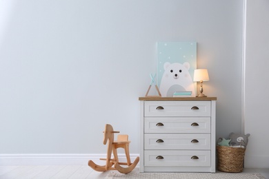 Photo of Modern white chest of drawers near light wall in child room, space for text. Interior design