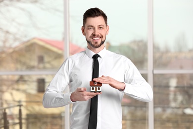 Real estate agent holding house model, indoors