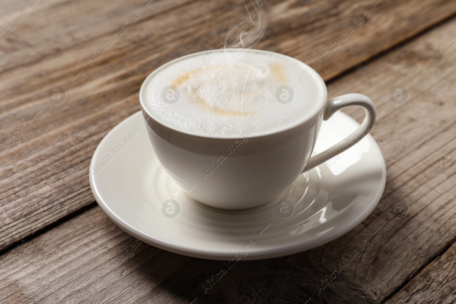 Image of Steaming coffee in cup on wooden table