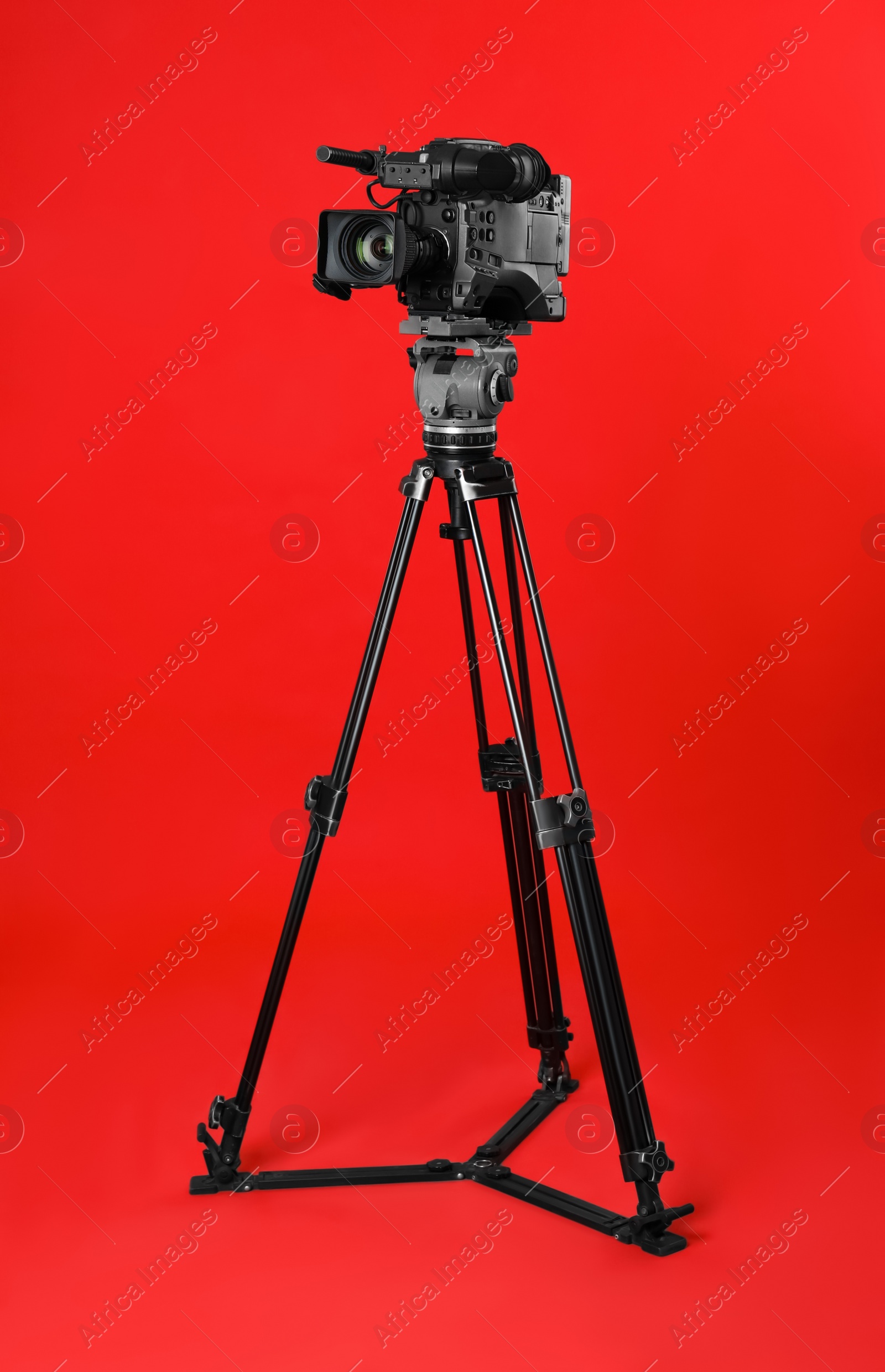 Photo of Modern professional video camera on red background