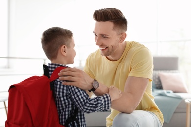 Young man helping his little child get ready for school at home