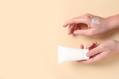 Photo of Woman with tube of hand cream on beige background, top view. Space for text