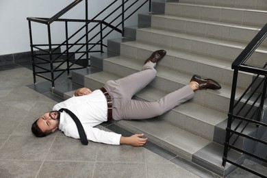 Photo of Unconscious man lying after falling down stairs indoors